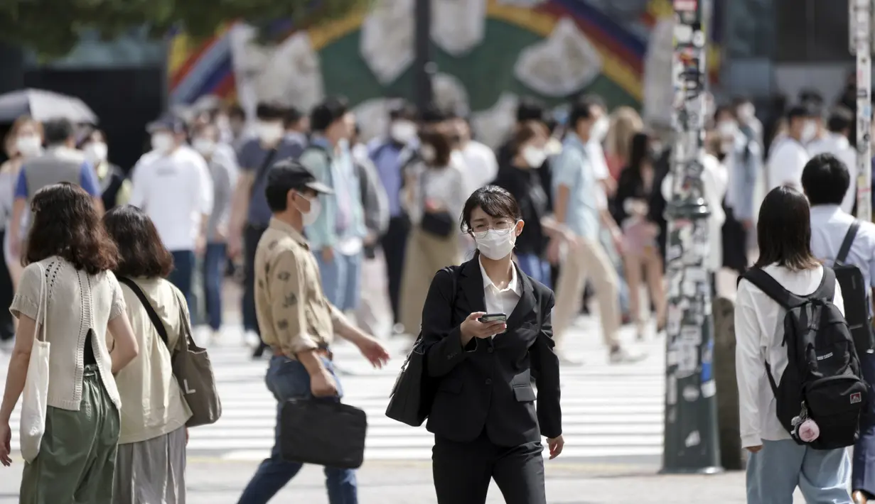 Orang-orang yang memakai masker berjalan di sepanjang penyeberangan pejalan kaki di distrik Shibuya, Tokyo, Kamis (30/9/2021). Jepang akan mencabut keadaan darurat Covid-19 mulai Kamis ini karena jumlah kasus baru turun dan tekanan pada sistem medis mereda. (AP Photo/Eugene Hoshiko)