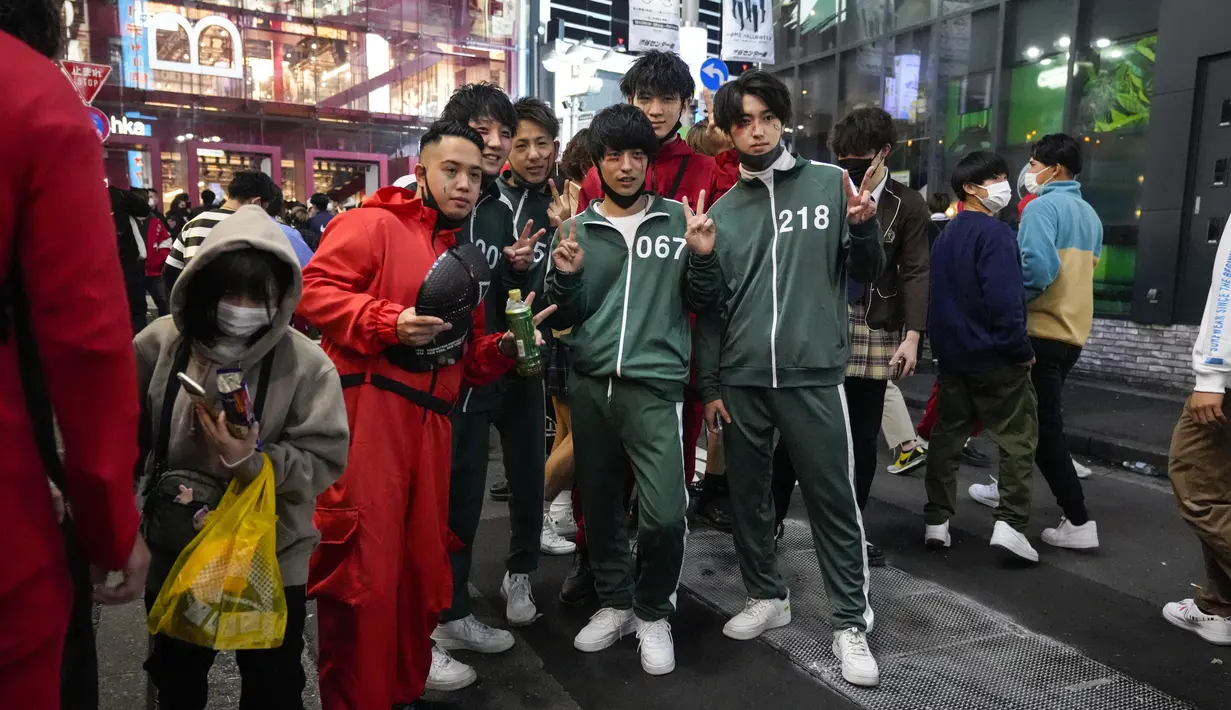 Pejalan kaki dengan kostum Halloween berfoto ketika ribuan orang berkumpul di distrik Shibuya, Tokyo, Minggu (31/10/2021). Sebanyak 500 polisi anti huru-hara Kepolisian Metropolitan Tokyo dikerahkan untuk mengamankan perayaan malam Halloween sejak 30 hingga 31 Oktober. (AP Photo/Kiichiro Sato)