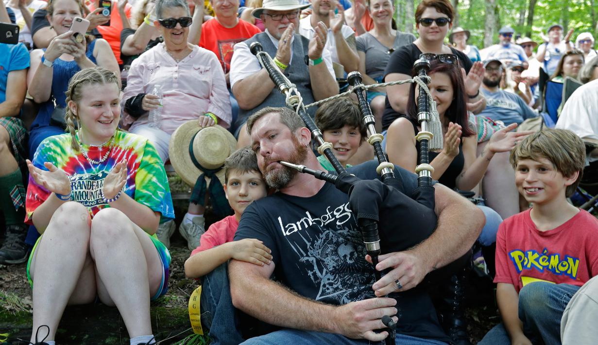 Neil Anderson dari band Seven Nations memainkan bagpipe-nya saat dia duduk bersama kerumunan orang selama acara Grandfather Mountain Highland Games ke-64 di MacRae Meadows, Linville, North Carolina, AS, Jumat (12/7/2019). (AP Photo/Chuck Burton)