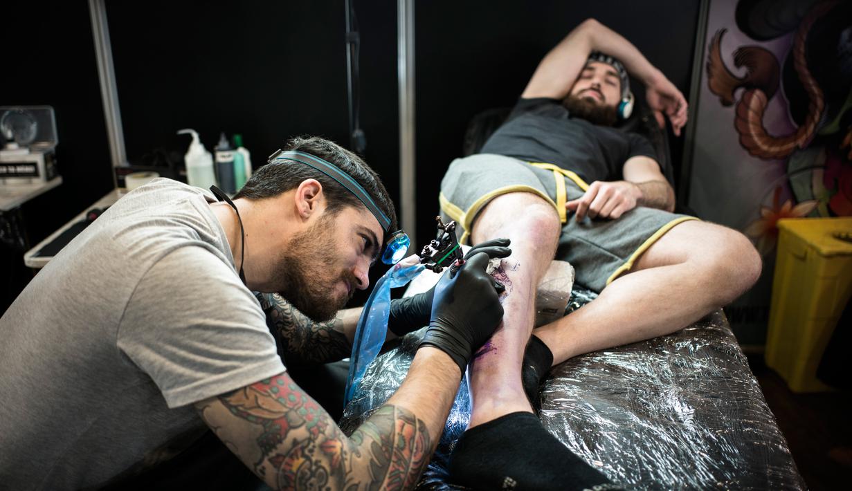 Seorang pria membuat tato saat Paris Tattoo Convention di Grand Halle de la Villette, Paris, Prancis, Jumat (9/3). Paris Tattoo Convention berlangsung dari tanggal 9 sampai 11 Maret. (Philippe LOPEZ/AFP)