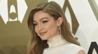 Gigi Hadid tersenyum saat tiba menghadiri CMA Awards tahunan ke-53 di Bridgestone Arena di Nashville, Tennessee (13/11/2019). Model berusia 24 tahun ini tampil memukau dalam balutan gaun putih. (AP Photo/Evan Agostini)