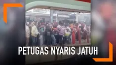Desakan antrean di peron stasiun membuat seorang petugas nyaris jatuh ke rel kereta.