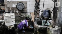 Warga mencuci piring menggunakan air dari sumur timba di kawasan Sukapura, Cilincing, Jakarta, Senin (22/3/2021). Meski kondisi air jernih dan tawar, warga setempat tidak menggunakan air sumur timba untuk konsumsi. (merdeka.com/Iqbal S. Nugroho)