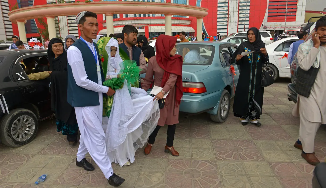 Sepasang suami istri Afghanistan meninggalkan aula pernikahan setelah upacara pernikahan massal di Kabul, Afghanistan, 13 Juni 2022. Upacara pernikahan dihadiri ratusan tamu dan pejuang Taliban yang membawa senjata. (Sahel ARMAN/AFP)