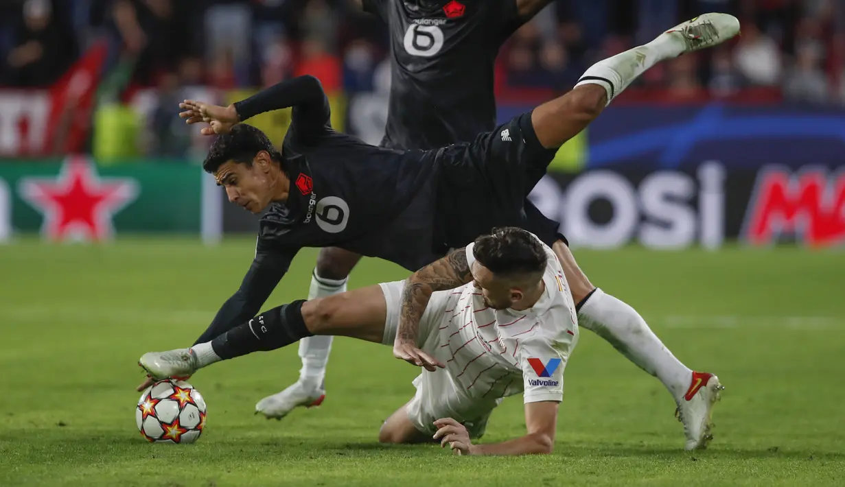 Gelandang Sevilla, Lucas Ocampos berebut bola dengan gelandang Lille, Benjamin Andre pada babak lanjutan Grup G Liga Champions di stadion Ramon Sanchez Pizjuan, Rabu (3/11/2021) dinihari WIB. Sevilla tumbang 1-2 di tangan Lille. (AP Photo/Angel Fernandez)