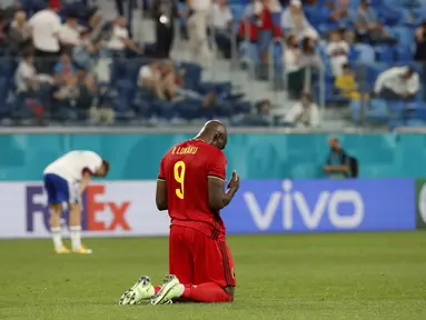 Penyerang timnas Belgia, Romelu Lukaku berlutut di lapangan pada akhir Matchday 1 Grup B Euro 2020 kontra Rusia di Stadion Saint-Petersburg, Minggu (13/6/2021) dini hari WIB. Rusia berhasil mengandaskan Rusia dengan skor 3-0 dengan dua gol dari Romelu Lukaku. (Anatoly Maltsev/Pool via AP)