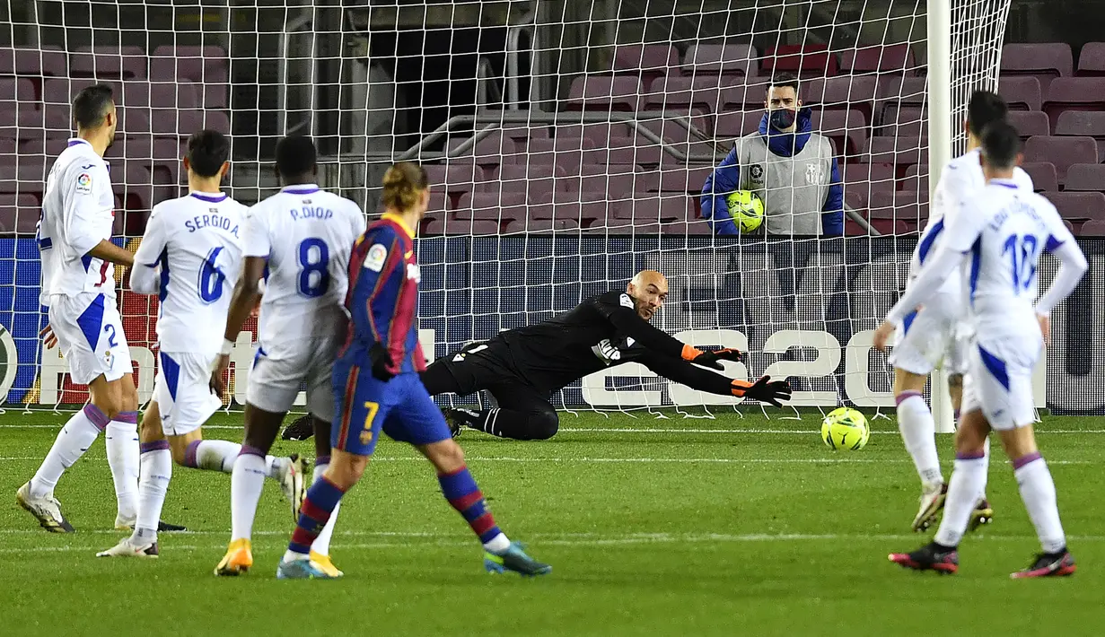 Kiper Eibar, Marko Dmitrovic (kiri) mementahkan tendangan bebas gelandang Barcelona, Antoine Griezmann dalam laga lanjutan Liga Spanyol 2020/21 pekan ke-16 di Camp Nou, Selasa (29/12/2020). Eibar bermain imbang 1-1 dengan Barcelona. (AFP/Pau Barrena)