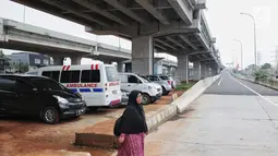 Seorang wanita melintas dekat sejumlah mobil yang terparkir di bawah kolong tol Becakayu Kalimalang, Jakarta Timur, Selasa (12/2). Lahan kosong di bawah kolong tol Becakayu disalahgunakan menjadi parkir liar. (Liputan6.com/Faizal Fanani)