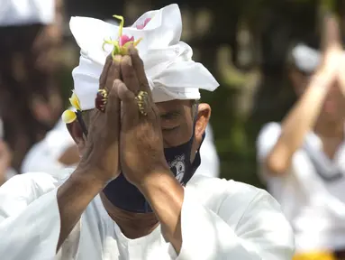Seorang pria yang memakai masker bersembahyang saat Hari Raya Galungan di sebuah pura di Bali, Rabu (14/4/2021). Perayaan Hari Raya Galungan yang merupakan hari kemenangan kebenaran (Dharma) atas kejahatan (Adharma) itu diikuti umat Hindu dengan menerapkan protokol kesehatan. (AP/Firdia Lisnawati)