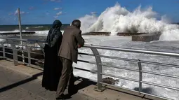 Pasangan suami istri melihat terjangan ombak di dinding laut Fishers Marina, di tepi pantai Corniche, atau promenade tepi laut, di Beirut, Lebanon (26/10). (AP Photo / Hussein Malla)