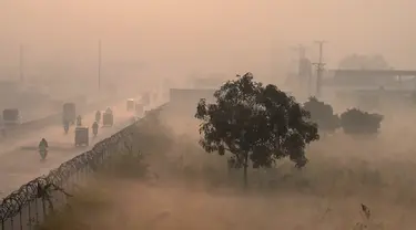 Orang-orang bepergian di sepanjang jalan di tengah kondisi kabut asap tebal di Lahore, Pakistan, Kamis (18/11/2021). Lahore telah dinyatakan sebagai kota dengan tingkat polusi udara tertinggi di dunia saat kabut asap beracun tebal melanda kota tersebut. (Arif ALI/AFP)