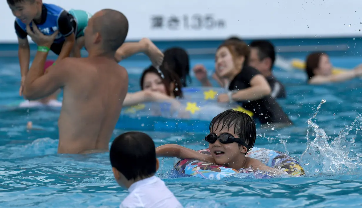 Pengunjung menghabiskan waktu di kolam renang di sebuah taman hiburan di Tokyo, Jepang (19/7). Badan Meteorologi Jepang mengumumkan Jepang tengah, termasuk Tokyo, telah menyelesaikan musim hujan 'Tsuyu'.  (AFP Photo/Toshifumi Kitamura)