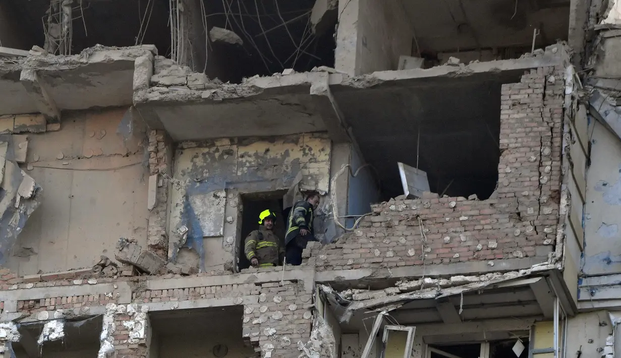 Tim penyelamat melakukan upaya pencarian korban di sebuah bangunan tempat tinggal bertingkat, yang sebagian hancur setelah serangan pesawat tak berawak pada malam hari di Kyiv pada 30 Mei 2023. (Sergei SUPINSKY/AFP)
