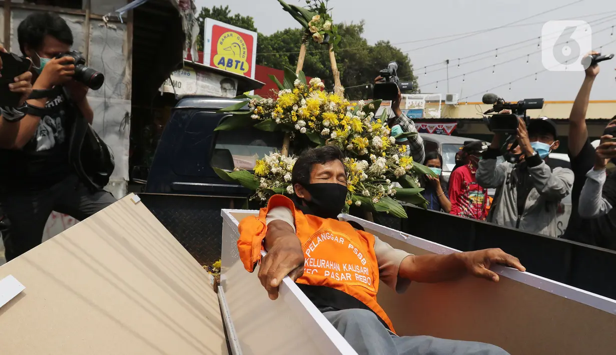 Warga pelanggar PSBB saat keluar dari peti mati di Kawasan Kalisari, Pasar Rebo, Jakarta Timur, Kamis (3/9/2020). Warga Pasar Rebo yang kedapatan keluar rumah tanpa menggunakan masker diberikan pilihan hukuman, salah satunya dimasukkan ke dalam peti mati selama 1 menit. (Liputan6.com/Herman Zakharia