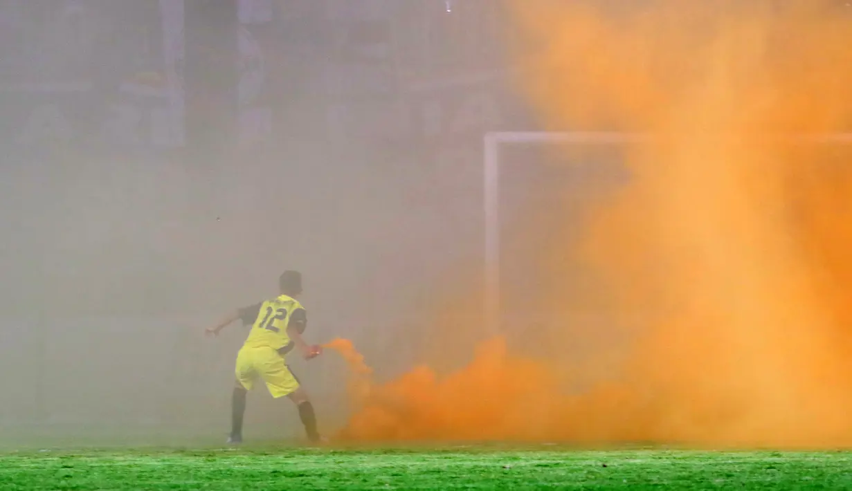 Seorang anak Gawang mengeluarkan flare yang dilempar Suporter Arema Cronus saat memberi dukungan kepada timnya  pada lanjutan Piala Jenderal Sudirman grup E  di Stadion Sleman, Yogyakarta, Minggu (13/12/2015). (Bola.com/Nicklas Hanoatubun)