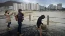 Seorang wanita mengambil gambar ombak yang menghantam hingga ke jalan saat serangan badai di Cape Town, Afrika Selatan, Rabu (7/6). Media setempat melaporkan beberapa orang tewas oleh kuatnya badai yang menghantam kawasan tersebut (RODGER BOSCH / AFP)