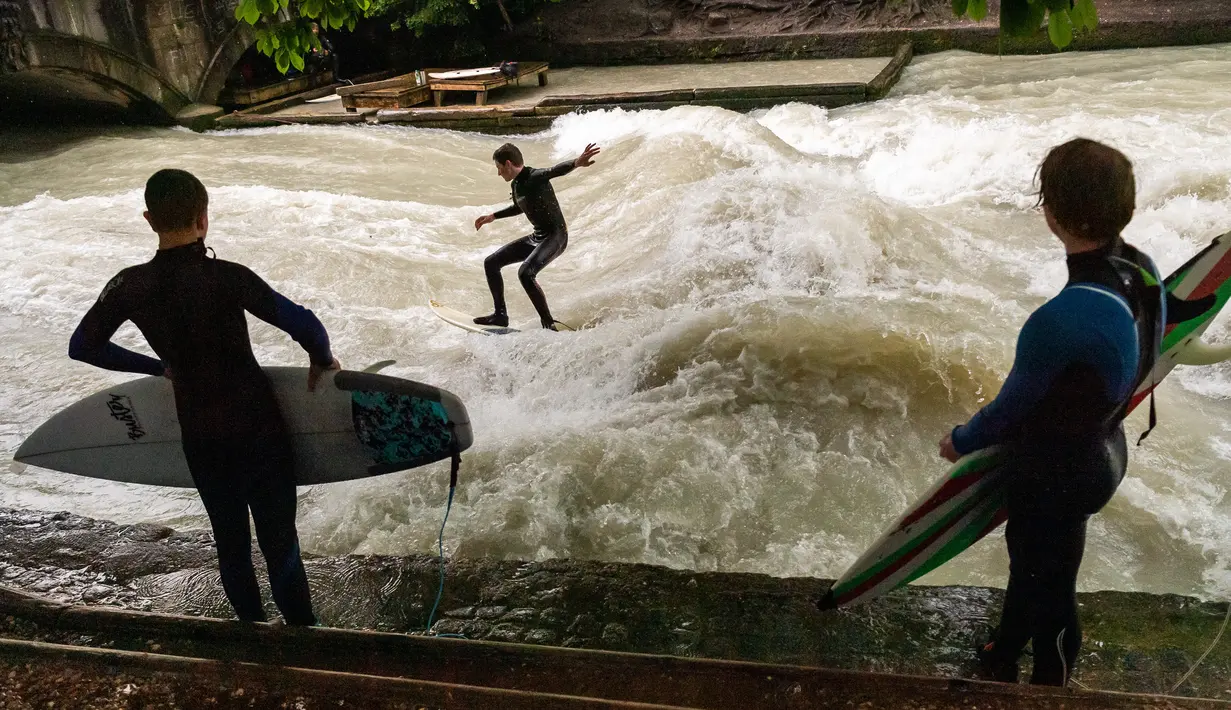 Peselancar meniti ombak saat bermain "surfing" di sungai buatan Eisbach yang terletak di English Garden Munich, Jerman pada 28 Mei 2019. Eisbach merupakan salah satu tempat berselancar sungai yang paling populer di kota Munich. (Photo by Peter Kneffel/dpa/AFP)