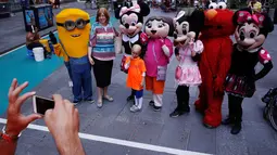 Seorang pengunjung berfoto bersama sejumlah karakter kartun di Times Square, New York, Selasa (21/6). Kehadiran karakter-karakter kartun tersebut mengundang warga untuk foto bersama. (REUTERS/Lucas Jackson)