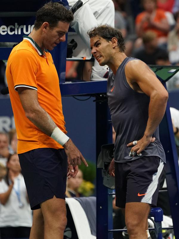 Petenis Spanyol, Rafael Nadal berbincang dengan Juan Martin del Potro dari Argentina setelah mengundurkan diri pada laga semifinal AS Terbuka 2018, Jumat (7/9). Nadal tak mampu melanjutkan pertandingan disebabkan cedera lutut. (AFP/kena betancur)