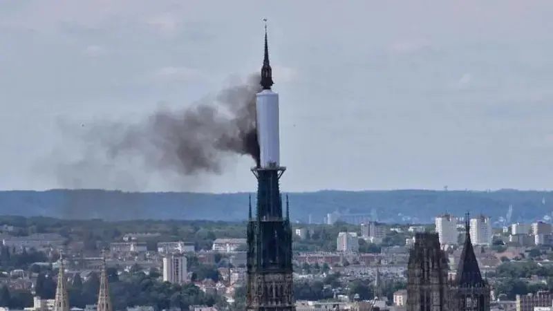 Asap terlihat mengepul dari bawah penutup yang mengelilingi puncak menara  katedral Gotik yang terkenal di Kota Rouen, Prancis. (AFP)