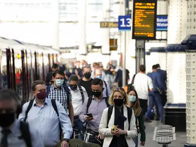 Orang-orang memakai masker setelah turun dari kereta api pada jam sibuk pagi hari di stasiun Waterloo di London, Rabu (13/7/2021). Wali Kota Sadiq Khan menekankan transportasi publik di London akan terus memberlakukan kewajiban memakai masker setelah Senin (19/7) mendatang. (AP Photo/Matt Dunham)
