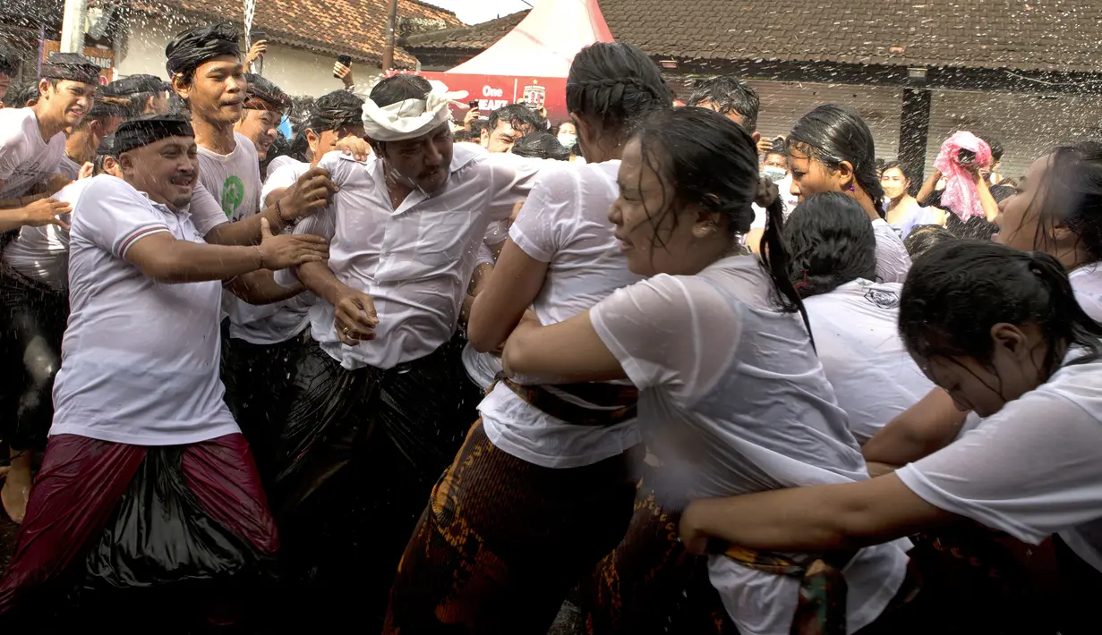 Seorang pria mencoba memeluk seorang wanita selama tradisi Omed-omedan (cium-ciuman) di Denpasar, Bali, Jumat (4/3/2022). "Omed-omedan" merupakan ritual tradisi khas muda-mudi yang dilaksanakan sehari setelah Hari Raya Nyepi. (AP Photo/Firdia Lisnawati)
