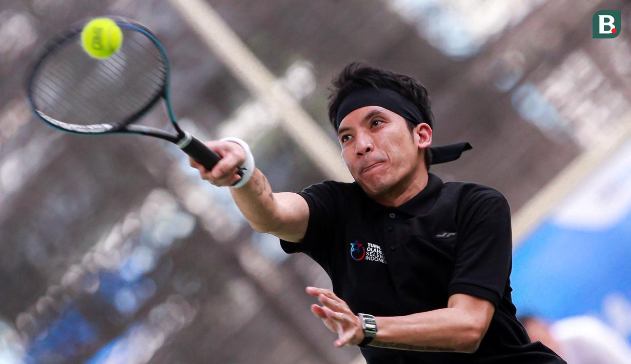 Selebritas Indonesia, Deddy Mahendra Desta berusaha mengembalikan bola ke arah pasangan Rezky Aditya dan Tanta Ginting pada laga tenis nomor ganda putra Turnamen Olahraga Selebriti Indonesia di GOR UNJ, Jakarta, Minggu (30/07/2023). Desta yang berpasangan dengan Raffi Ahmad menang dengan skor 4-6, 6-4, dan 6-4. (Bola.com/Bagaskara Lazuardi)