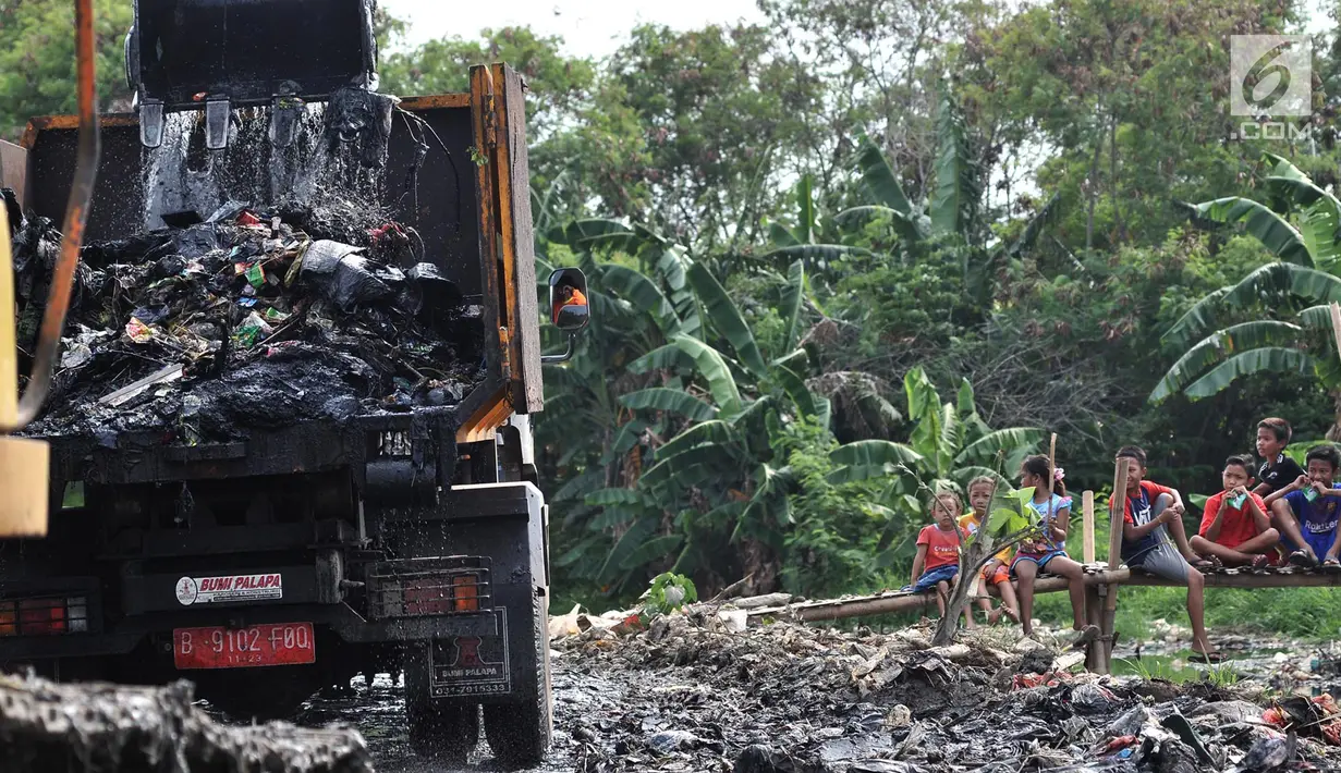 Anak-anak menyaksikan pengerukan sampah Kali Pisang Batu, Tarumajaya, Bekasi, Jawa Barat, Rabu (9/1). Petugas DLH Kabupaten Bekasi mulai membersihkan sampah setelah fenomena tersebut ramai diberitakan di media sosial. (Merdeka.com/Iqbal S. Nugroho)