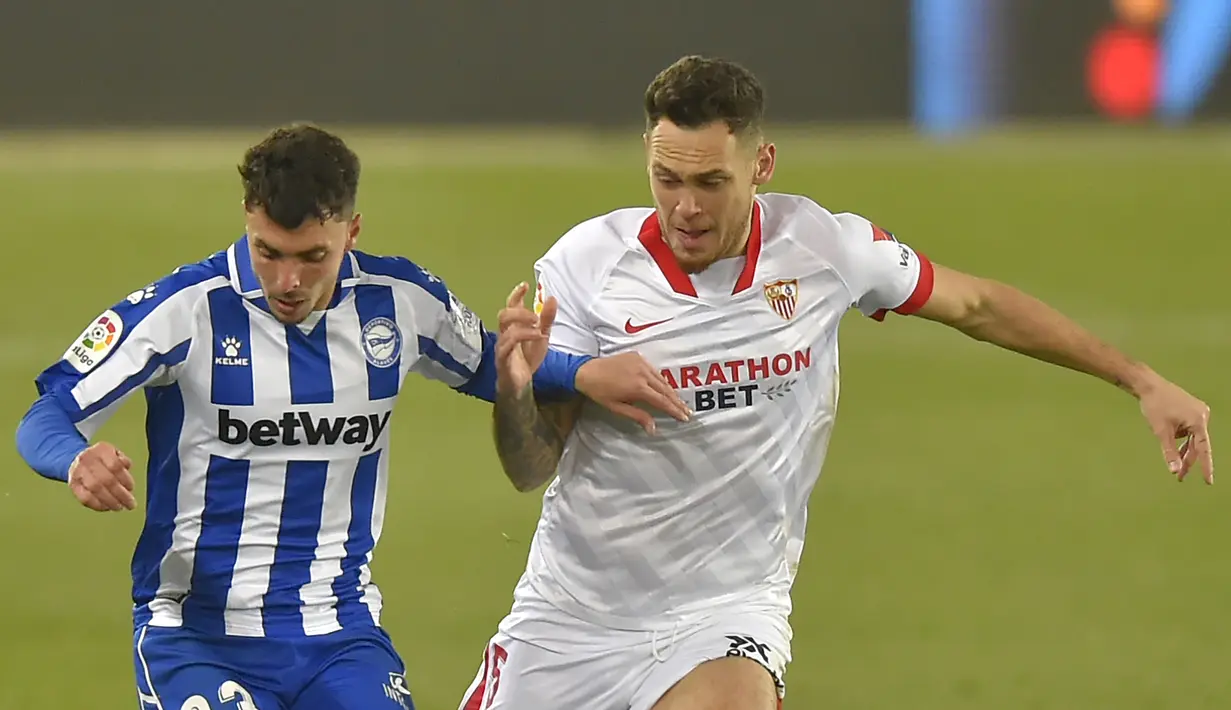 Penyerang Sevilla, Lucas Ocampos, berebut bola dengan bek Alaves, Joaquin Navarro, pada laga lanjutan Liga Spanyol di Stadion Mendizorrotza, Rabu (20/1/2021) dini hari WIB. Sevilla menang 2-1 atas Alaves. (AFP/Ander Gillenea)