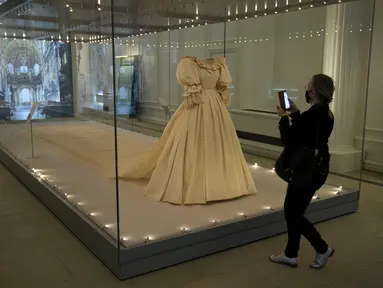 Jurnalis berdiri di samping gaun pengantin Putri Diana selama pratinjau media untuk pameran "Royal Style in the Making" di Istana Kensington di London, Rabu (2/6/2021). Pameran yang dibuka untuk pengunjung pada Kamis, 3 Juni 2021, ini akan berlangsung hingga 2 Januari 2022. (AP Photo/Matt Dunham)