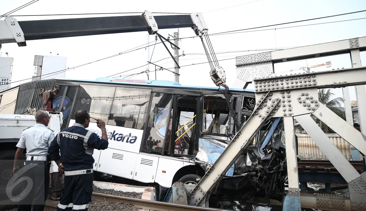 Petugas mengamati evakuasi bus transjakarta usai ditabrak kereta Senja Utama Solo di perlintasan Jalan Mangga Dua, Jakarta, Kamis (19/5). Menurut keterangan, insiden itu disebabkan bus Transjakarta yang menerobos palang pintu. (Liputan6.com/Faizal Fanani)