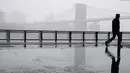 Seorang pejalan kaki melintas di dekat jembatan Manhattan saat badai salju di bawah drive Franklin Delano Roosevelt di New York (21/3). Badai salju yang melanda sebagian Amerika Serikat telah membawa salju dan angin kencang. (AP Photo / Mary Altaffer)