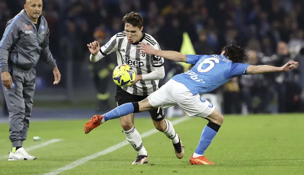 Pemain Juventus, Federicho Chiesa, terjatuh saat berusaha melewati pemain Napoli, Mario Rui, pada laga Liga Italia di Stadion  Diego Armando Maradona, Naples, (13/1/2023). Pengurangan poin itu berdampak signifikan pada posisi Bianconeri di klasemen. Dari yang awalnya di posisi tiga, kini langsung berada di posisi sepuluh klasemen sementara. (Alessandro Garofalo/LaPresse via AP)
