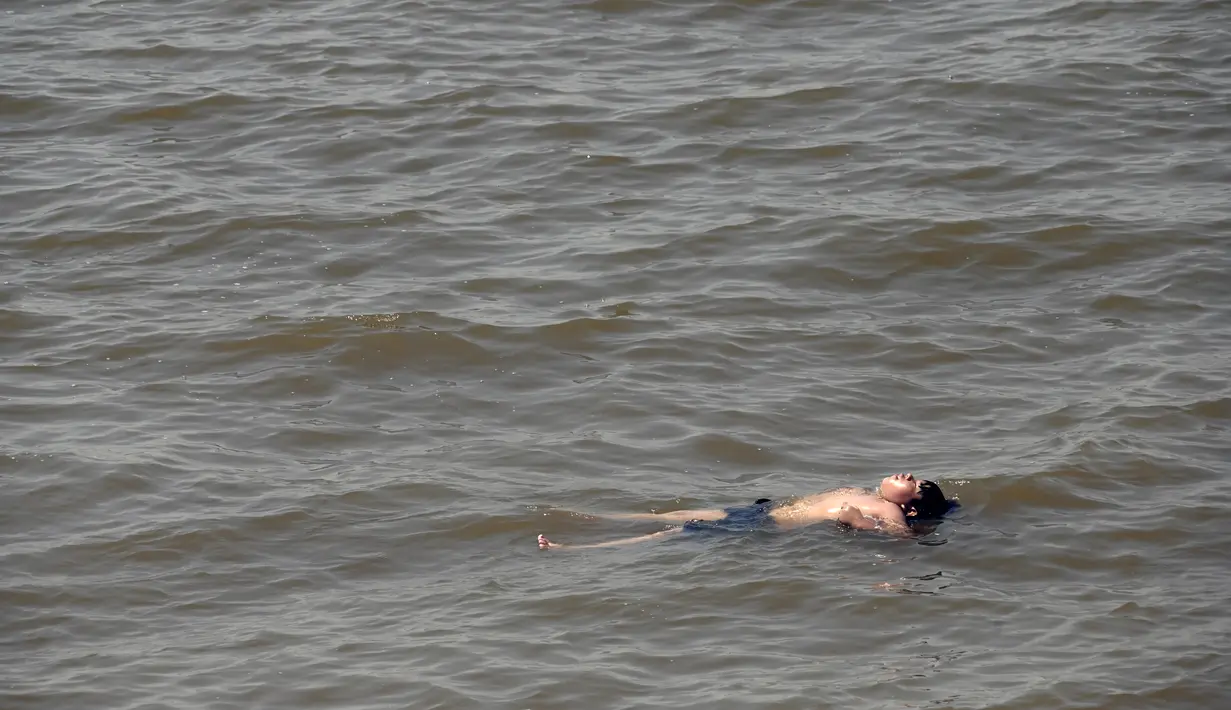Seorang pemuda melakukan pendinginan di Rio de la Plata di tengah gelombang panas musim panas di Buenos Aires, Argentina (14/1/2022).  Suhu tersebut membuat Argentina menjadi tempat paling panas di Bumi di awal tahun. (AP Photo/Mario De Fina)