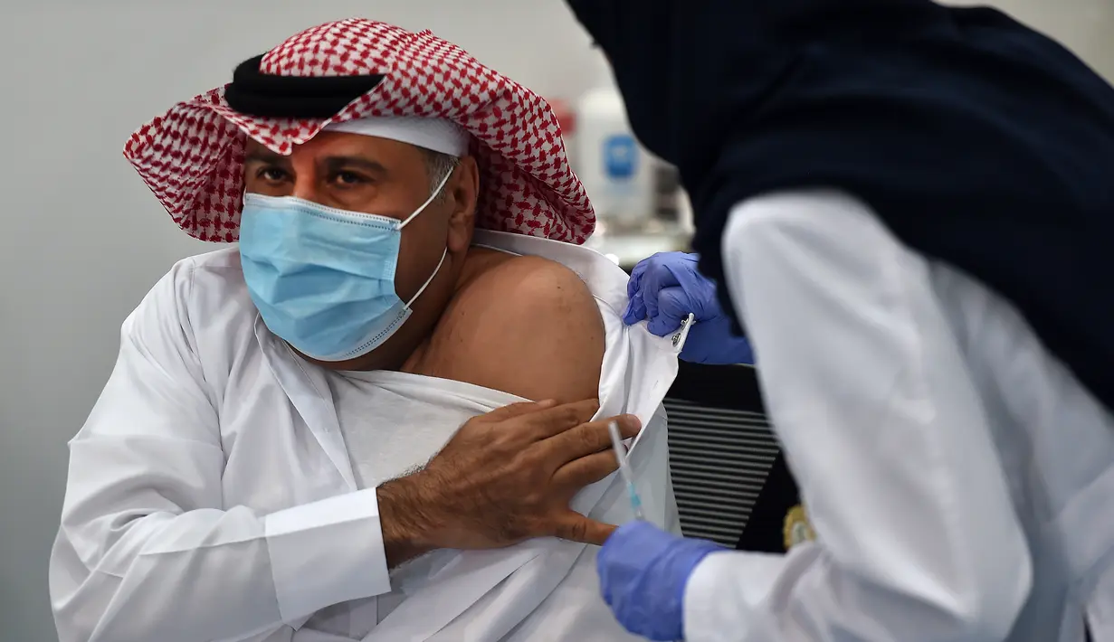 Warga sipil pertama saat menjalani penyuntikan vaksin Covid-19 di pusat vaksinasi yang diawasi Kementerian Kesehatan Arab Saudi di Riyadh, Arab Saudi, Kamis (17/12/2020). Arab Saudi akhirnya memulai vaksinasi Covid-19 setelah menerima dua pengiriman vaksin Pfizer-BioNTech. (AFP/Fayez Nureldine)