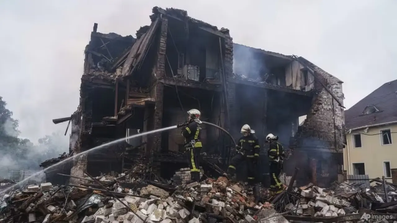 Petugas penyelamat memadamkan api di sebuah rumah yang hancur akibat serangan Rusia di desa Markhalivka, wilayah Kyiv, Ukraina, Minggu, 25 Mei 2025. (AP/Evgeniy Maloletka)