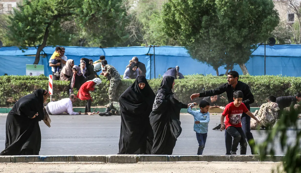 Seorang pria membantu wanita dan anak-anak melarikan diri saat terjadi serangan pada parade militer di Ahvaz, Iran, Sabtu (22/9). Hampir separuh yang tewas dalam serangan Ahvaz adalah anggota Garda Revolusi. (MORTEZA JABERIAN/ISNA/AFP)