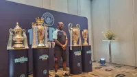 Mantan pemain Manchester City, Shaun Wright-Phillips, berfoto di depan empat trofi yang diraih The Citizen musim lalu. Trofi tersebut dipamerkan di hadapan media, di Hotel Double Three Jakarta, Indonesia, Kamis (28/9/2023). (Bola.com/Yus Mei Sawitri)