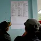 Anggota keluarga melihat daftar korban tenggelamnya KM Sinar Bangun di Danau Toba, Sumatera Utara, Selasa (19/6). Pencarian dan upaya penyelamatan dilakukan oleh Tim Gabungan Basarnas, Marinir dan kepolisian. (Jon NST/AFP)