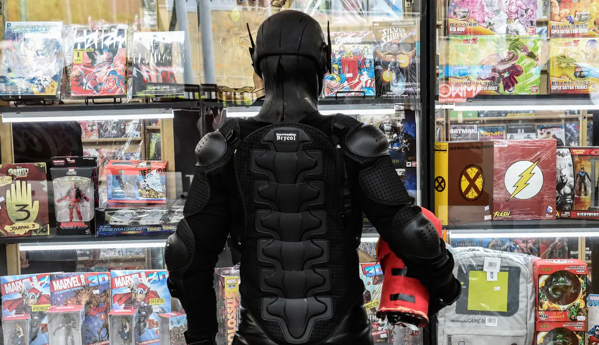 Seorang cosplay berkostum Black Racer melihat komik selama Comic Con Colombia 2018 di Medellin (16/11). Comic Con Colombia menyatukan penggemar dan pengusaha dari industri hiburan dan permainan berlangsung 16-18 November. (AFP Photo/Joaquin Sarmiento)