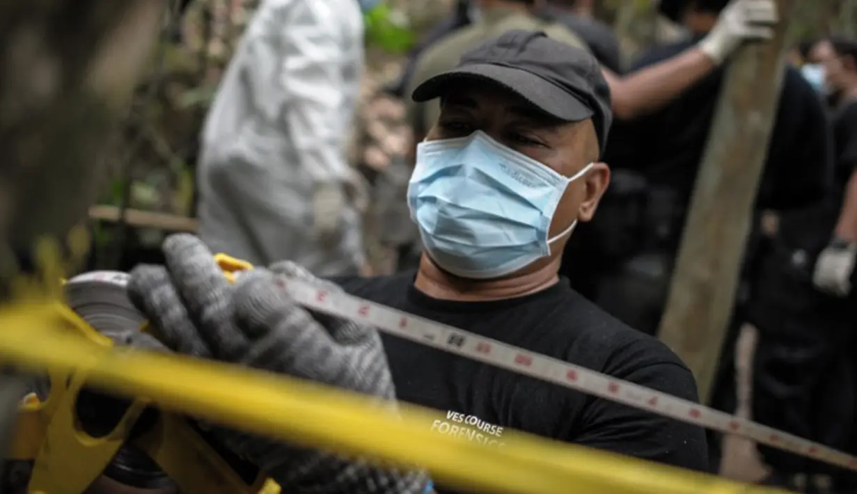Tim forensik Malaysia mengukur di lokasi kuburan massal di Wang Burma, dekat perbatasan Malaysia-Thailand, (26/5/2015). 139 kuburan massal yang berisi kerangka orang ditemukan.  (AFP PHOTO/MOHD RASFAN)