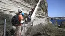 Turis menaiki tangga Raja Aragon di Bonifacio di pulau Corsica, Mediterania Prancis (19/9/2021). Pada kenyataannya, tangga itu digali oleh para biarawan Fransiskan untuk mengakses sumber air minum, yang tidak lagi digunakan. (AFP/Pascal Pochard-Casabianca)