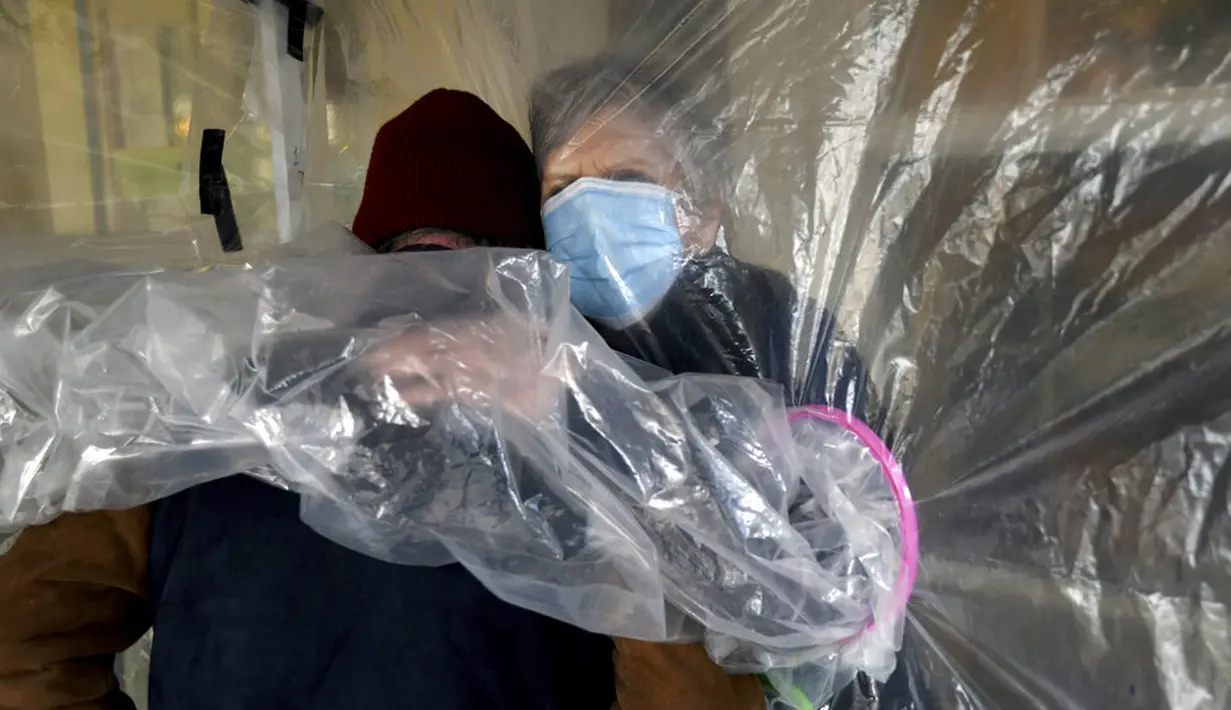 Lynda Hartman (75) memeluk suaminya Len Hartman (77) yang menderita demensia di tenda pelukan di luar pusat bantuan kehidupan Desa Juniper, Louisville, Cololardo, Amerika Serikat, 3 Februari 2021. Para lansia bisa memeluk orang tercinta meski menggunakan penghalang plastik. (AP Photo/Thomas Peipert)