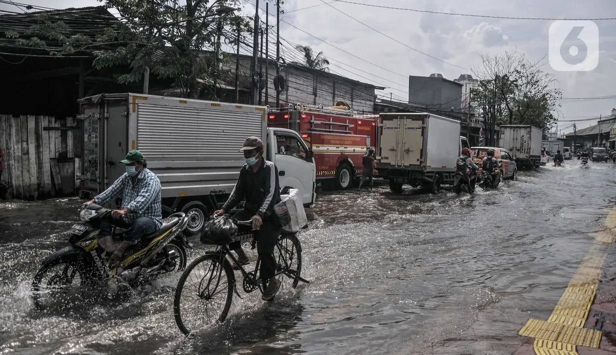 Arus lalu lintas tersendat saat melintasi banjir rob di Jalan Lodan Raya, Ancol, Jakarta, Senin (6/12/2021). Banjir akibat pasang air laut kembali merendam permukiman warga dan menggenangi Jalan Lodan Raya hingga ketinggian 50 cm yang menyebabkan kemacetan lalu lintas. (merdeka.com/Iqbal S Nugroho)