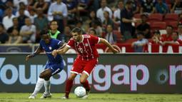 Gelandang Bayern Munchen, Javi Martinez, berebut bola dengan striker Chelsea, Michy Batshuayi pada laga turnamen pramusim ICC 2017 di Stadion Nasional Singapura, Selasa (25/7/2017). Bayern Munchen menang 3-2 atas Chelsea. (EPA/Wallace Woon)