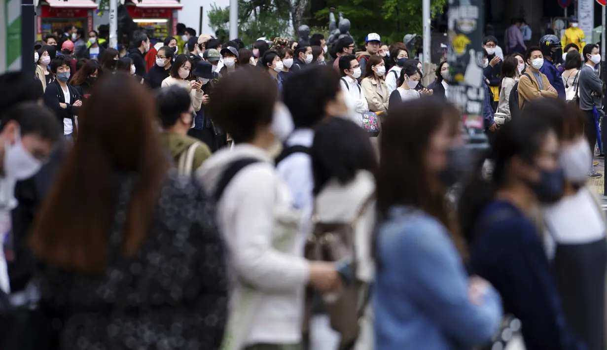 Orang-orang mengenakan masker untuk mencegah virus corona berjalan melintasi penyeberangan pejalan kaki pada awal liburan "Minggu Emas" Jepang di distrik Shibuya, Tokyo, Kamis (29/4/2021). (AP Photo/Eugene Hoshiko)