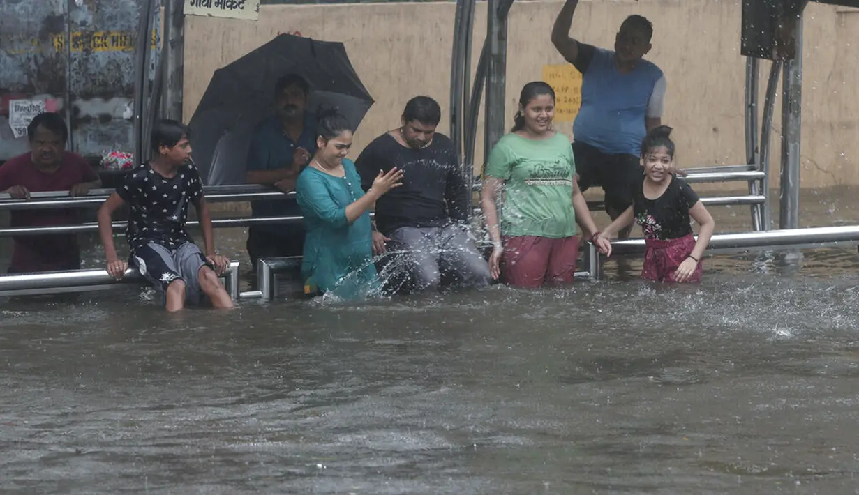 Anak-anak bermain di halte bus yang terendam banjir saat hujan lebat di Mumbai, India, Rabu (9/6/2021). Mumbai terendam banjir usai diguyur hujan lebat. (AP Photo/Rafiq Maqbool)