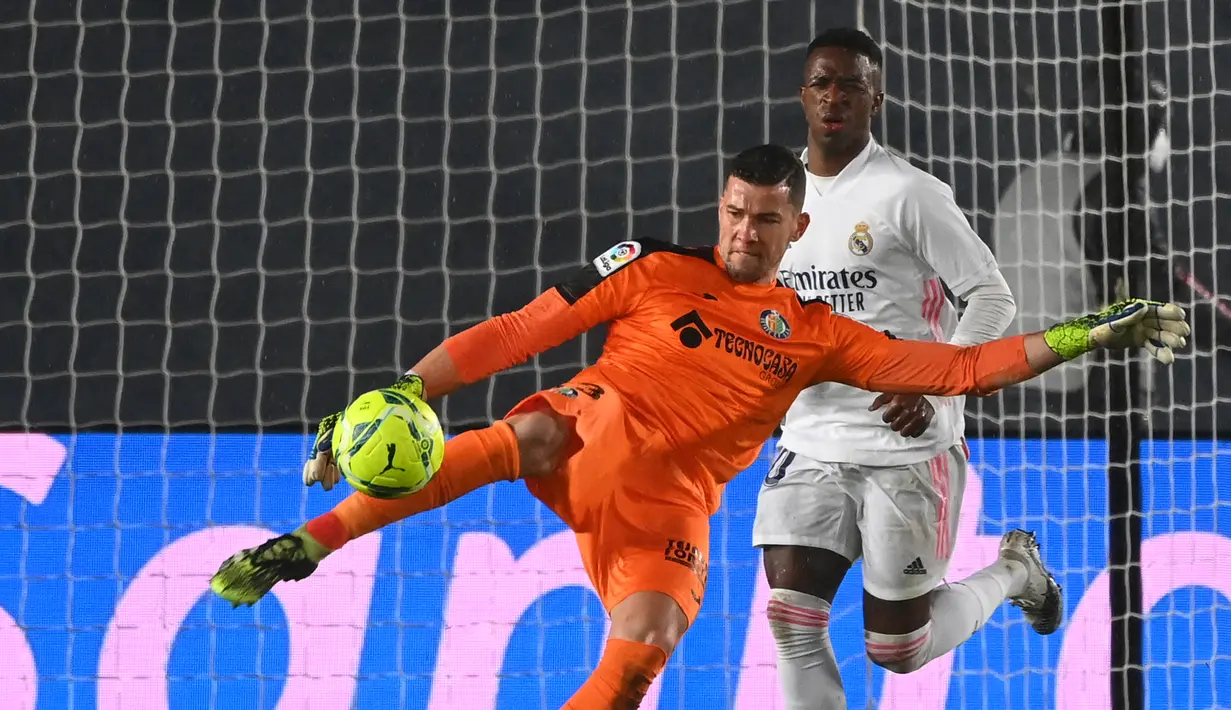 Kiper Getafe, David Soria melepaskan tendangan di depan striker Real Madrid, Vinicius Junior dalam laga lanjutan Liga Spanyol 2020/21 pekan ke-22 di Alfredo di Stefano Stadium, Selasa (9/2/2021). Getafe kalah 0-2 dari Real Madrid. (AFP/Gabriel Bouys)
