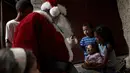 Santa Claus menghibur seorang balita saat mengunjungi kawasan kumuh Petare di Caracas, Venezuela (11/12). Kunjungan Santa Claus ini untuk menghibur anak-anak Petare dalam menyambut datangnya natal. (Reuters/Ueslei Marcelino)