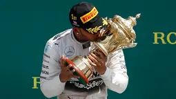 Pembalap Formula 1 tim Mercedes, Lewis Hamilton mencium piala yang diraihnya usai menjuarai Grand Prix Formula 1 Silverstone di Inggris, (5/7/2015). Hamilton berhasil finish di urutan pertama dengan waktu 1 jam 31 menit 27,729 detik. (Reuters/Phil Noble)